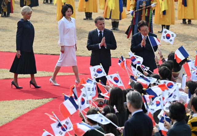 French President Emmanuel Macron (2nd R), his wife Brigitte Macron (L) and South Korean President Lee Jae Myung (R) and his wife Kim Hea Kyung (2nd L) attend the welcome ceremony at the presidential Blue House in Seoul on April 3, 2026. (Photo by JUNG YEON-JE / POOL / AFP)