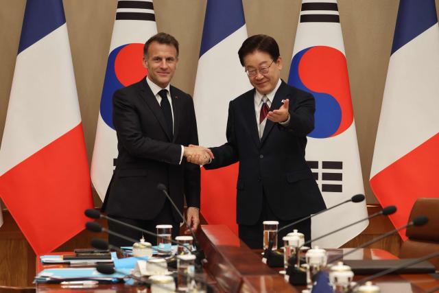 French President Emmanuel Macron (L) shakes hands with South Korean President Lee Jae Myung before their bilateral meeting in Seoul on April 3, 2026. (Photo by Ludovic MARIN / AFP)