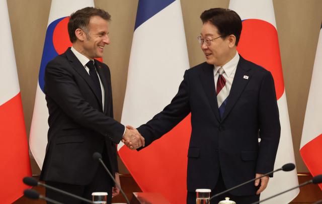 French President Emmanuel Macron (L) shakes hands with South Korean President Lee Jae Myung (R) during their meeting at the presidential Blue House in Seoul on April 3, 2026. (Photo by Ludovic MARIN / AFP)