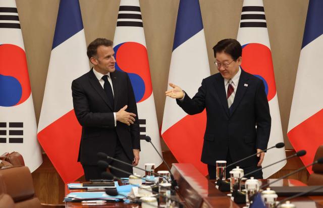 French President Emmanuel Macron (L) and South Korean President Lee Jae Myung gesture before their bilateral meeting in Seoul on April 3, 2026. (Photo by Ludovic MARIN / AFP)