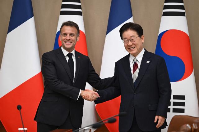 French President Emmanuel Macron (L) shakes hands with South Korean President Lee Jae Myung (R) during their meeting at the presidential Blue House in Seoul on April 3, 2026. (Photo by JUNG YEON-JE / POOL / AFP)