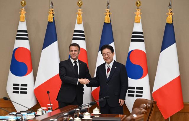 French President Emmanuel Macron (L) shakes hands with South Korean President Lee Jae Myung (R) during their meeting at the presidential Blue House in Seoul on April 3, 2026. (Photo by JUNG YEON-JE / POOL / AFP)