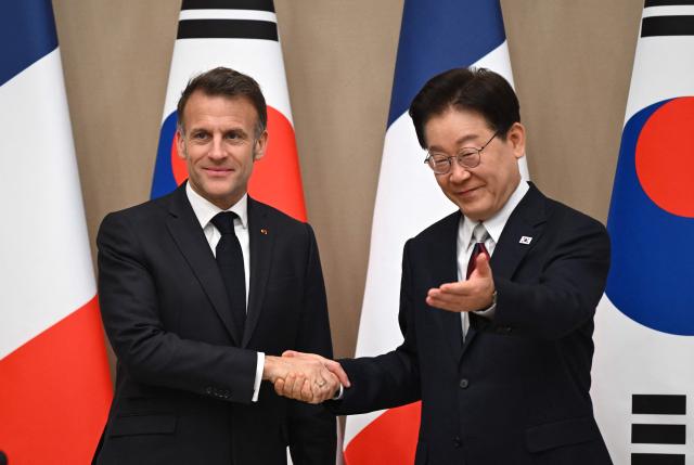 French President Emmanuel Macron (L) shakes hands with South Korean President Lee Jae Myung (R) during their meeting at the presidential Blue House in Seoul on April 3, 2026. (Photo by JUNG YEON-JE / POOL / AFP)