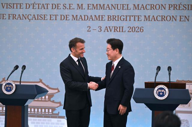 French President Emmanuel Macron (L) shakes hands with South Korean President Lee Jae Myung (R) during a joint press conference after their meeting at the presidential Blue House in Seoul on April 3, 2026. (Photo by JUNG YEON-JE / POOL / AFP)