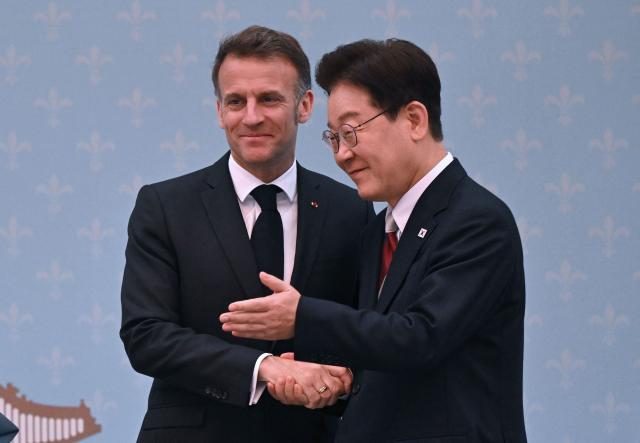 French President Emmanuel Macron (L) shakes hands with South Korean President Lee Jae Myung (R) during a joint press conference after their meeting at the presidential Blue House in Seoul on April 3, 2026. (Photo by JUNG YEON-JE / POOL / AFP)