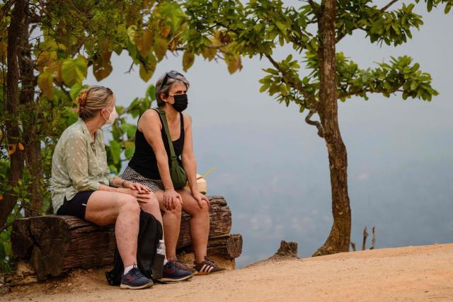 Tourists wear face masks as they visit a Kong Lan, or Pai Canyon, in Pai on April 1, 2026, west of Thailand's second-largest city Chiang Mai. Seasonal agricultural burning, forest fires and weather patterns produce an annual pollution season across much of Southeast Asia. But parts of northern Thailand are seeing haze that even hardened locals say is exceptional. (Photo by ANTHONY WALLACE / AFP) / To go with 'Thailand-Pollution-Environment-Fire-Health' Reportage by Chayanit ITTHIPONGMAETEE