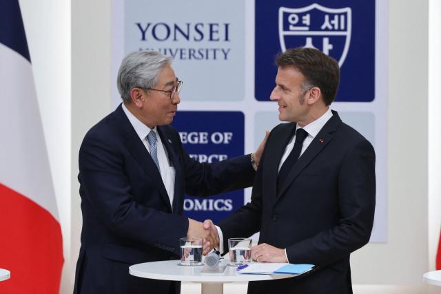 French President Emmanuel Macron (R) shakes hands with Yonsei University president Yoon Dong-sup during a meeting with students at Yonsei University in Seoul on April 3, 2026. (Photo by Ludovic MARIN / AFP)