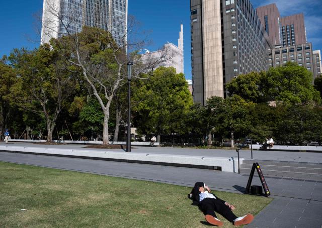 A man takes rests at Hibiya Park in Tokyo on April 3, 2026. (Photo by ANDREW CABALLERO-REYNOLDS / AFP)