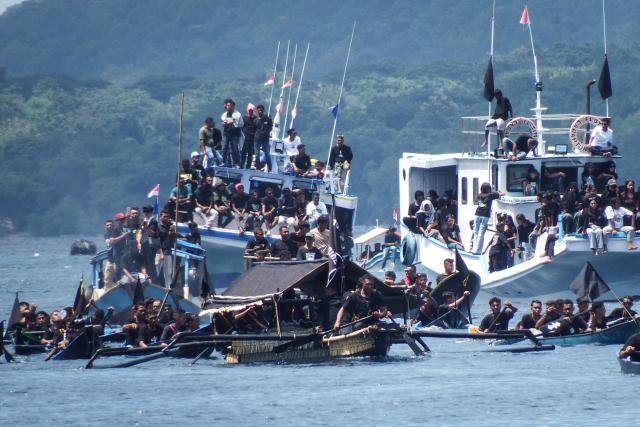 Catholic devotees transport a casket containing a statue of Jesus by boat during a Good Friday sea procession from Tuan Menino Chapel, a ritual inherited from Portuguese influence for over five centuries, in Larantuka, East Nusa Tenggara, on April 3, 2026. (Photo by ARNOLD WELIANTO / AFP)