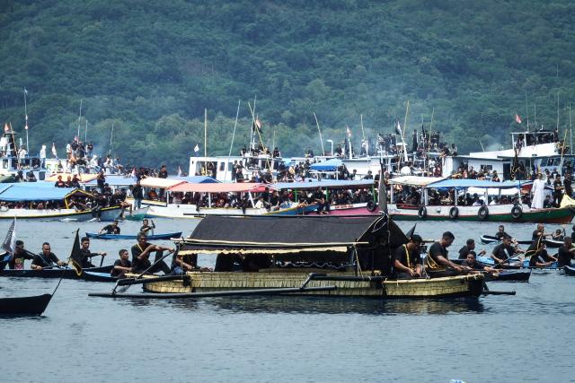 Catholic devotees transport a casket containing a statue of Jesus by boat during a Good Friday sea procession from Tuan Menino Chapel, a ritual inherited from Portuguese influence for over five centuries, in Larantuka, East Nusa Tenggara, on April 3, 2026. (Photo by ARNOLD WELIANTO / AFP)