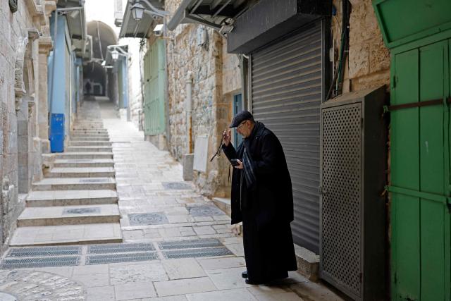A Catholic priest signs himself in front of the sixth station of the Via Dolorosa in the Old City of Jerusalem on April 3, 2026. Holy sites in Jerusalem's old city have remained closed for security reasons since the outbreak of the Middle East war on February 28, when Israel and the US launched strikes on Iran. (Photo by Marco Longari / AFP)
