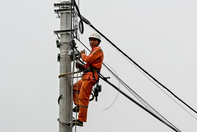An electrician works on power lines in Hanoi on April 3, 2026. (Photo by Nhac NGUYEN / AFP)