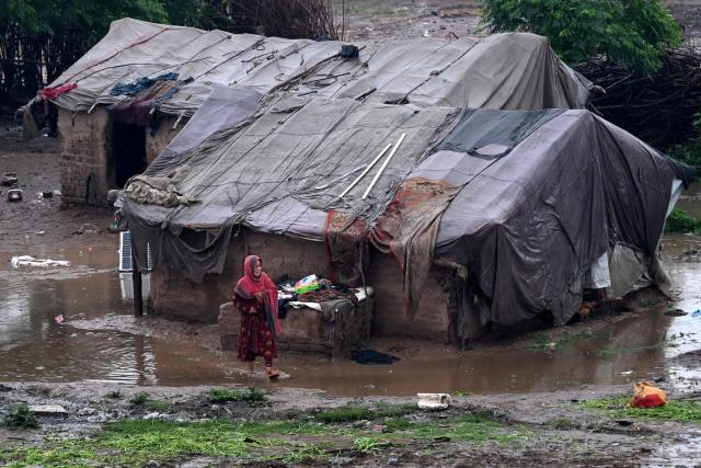 A girl walks through a pool of water near makeshift shelters after heavy rainfall in Peshawar on April 3, 2026. (Photo by Abdul MAJEED / AFP)