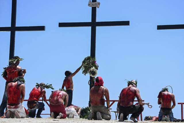 EDITORS NOTE: Graphic content / Penitents kneel in front of the crosses prior to the annual crucifixion during the observance of Lent in the village of Cutud in San Fernando, Pampanga province on April 3, 2026. Devotees in the fervently Catholic Philippines marked Good Friday by being nailed to crosses and whipping their backs bloody, in extreme acts of devotion that attracted thousands of spectators. (Photo by Ted ALJIBE / AFP)