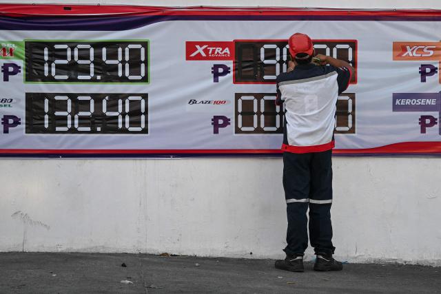 An employee changes the price signage of fuel at a petrol station in San Fernando, Pampanga province on April 3, 2026. (Photo by Ted ALJIBE / AFP)