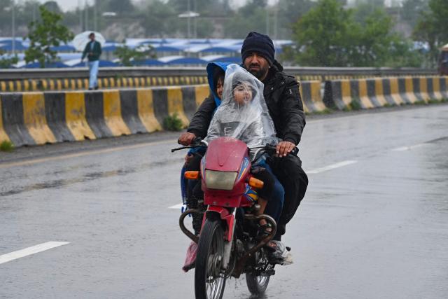 Commuters ride along a road during rainfall in Peshawar on April 3, 2026. (Photo by Abdul MAJEED / AFP)