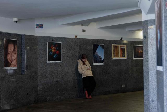 A girl uses a smartphone as she takes shelter at an underground walkway during an air strike alarm in Kyiv on April 3, 2026, amid the Russian invasion of Ukraine. (Photo by Tetiana DZHAFAROVA / AFP)
