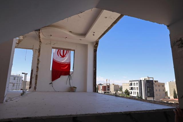 An Iranian flag is seen on a residential building that was damaged by recent strikes at Vahdat town in Karaj, southwest of Tehran on April 3, 2026. Iran and its allies traded fire with Israel and the United States, as Washington-linked assets across the Middle East were targeted alongside civilian infrastructure -- with the month-long war on April 3 showing little sign of easing. (Photo by ATTA KENARE / AFP) / 