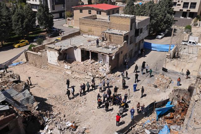 Media representatives gather around a residential building that was damaged by recent strikes at Vahdat town in Karaj, southwest of Tehran on April 3, 2026. Iran and its allies traded fire with Israel and the United States, as Washington-linked assets across the Middle East were targeted alongside civilian infrastructure -- with the month-long war on April 3 showing little sign of easing. (Photo by ATTA KENARE / AFP) / 