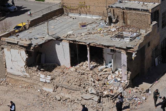 Media representatives gather around a residential building that was damaged by recent strikes at Vahdat town in Karaj, southwest of Tehran on April 3, 2026. Iran and its allies traded fire with Israel and the United States, as Washington-linked assets across the Middle East were targeted alongside civilian infrastructure -- with the month-long war on April 3 showing little sign of easing. (Photo by ATTA KENARE / AFP) / 