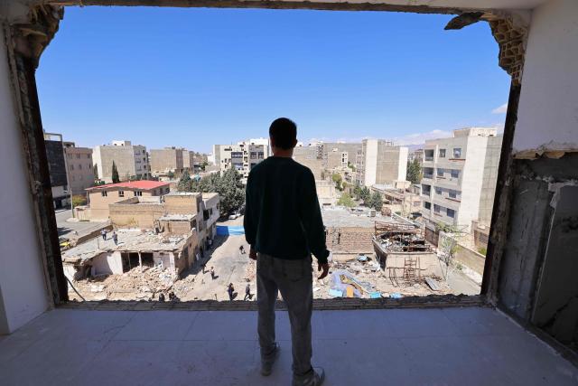 A man looks at the residential buildings that were damaged by recent strikes at Vahdat town in Karaj, southwest of Tehran on April 3, 2026. Iran and its allies traded fire with Israel and the United States, as Washington-linked assets across the Middle East were targeted alongside civilian infrastructure -- with the month-long war on April 3 showing little sign of easing. (Photo by ATTA KENARE / AFP) / 
