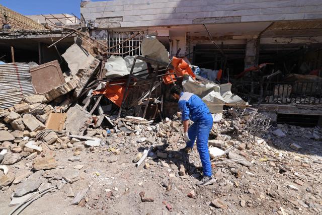 A man inspects the debris of residential buildings that were damaged by recent strikes at Vahdat town in Karaj, southwest of Tehran on April 3, 2026. Iran and its allies traded fire with Israel and the United States, as Washington-linked assets across the Middle East were targeted alongside civilian infrastructure -- with the month-long war on April 3 showing little sign of easing. (Photo by ATTA KENARE / AFP) / 