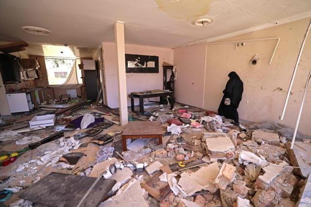 A woman stands amid the destroyed belongings of her house that was damaged by recent strikes at Vahdat town in Karaj, southwest of Tehran on April 3, 2026. Iran and its allies traded fire with Israel and the United States, as Washington-linked assets across the Middle East were targeted alongside civilian infrastructure -- with the month-long war on April 3 showing little sign of easing. (Photo by ATTA KENARE / AFP) / 