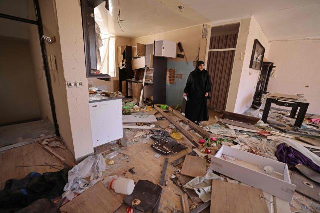 A woman stands amid the destroyed belongings of her house that was damaged by recent strikes at Vahdat town in Karaj, southwest of Tehran on April 3, 2026. Iran and its allies traded fire with Israel and the United States, as Washington-linked assets across the Middle East were targeted alongside civilian infrastructure -- with the month-long war on April 3 showing little sign of easing. (Photo by ATTA KENARE / AFP) / 