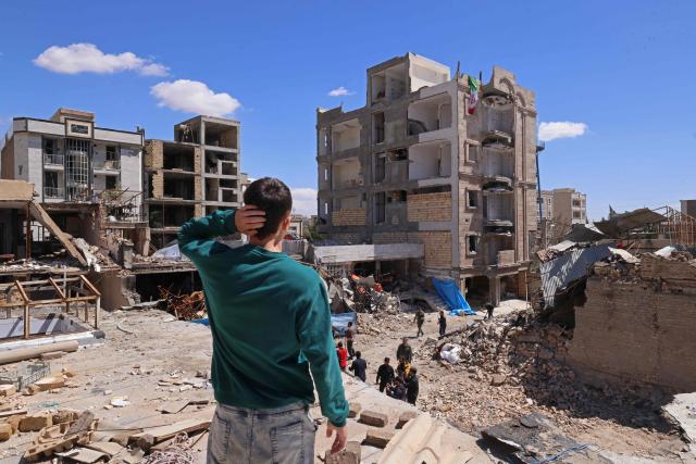 A man looks at the residential buildings that were damaged by recent strikes at Vahdat town in Karaj, southwest of Tehran on April 3, 2026. Iran and its allies traded fire with Israel and the United States, as Washington-linked assets across the Middle East were targeted alongside civilian infrastructure -- with the month-long war on April 3 showing little sign of easing. (Photo by ATTA KENARE / AFP) / 