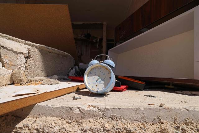 A clock is pictured amid the debris of a residential apartment that was damaged by recent strikes at Vahdat town in Karaj, southwest of Tehran on April 3, 2026. Iran and its allies traded fire with Israel and the United States, as Washington-linked assets across the Middle East were targeted alongside civilian infrastructure -- with the month-long war on April 3 showing little sign of easing. (Photo by ATTA KENARE / AFP) / 