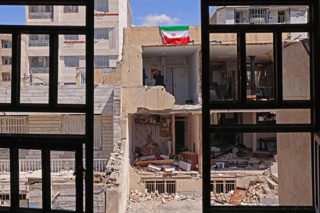 An Iranian flag is seen on a residential building that was damaged by recent strikes at Vahdat town in Karaj, southwest of Tehran on April 3, 2026. Iran and its allies traded fire with Israel and the United States, as Washington-linked assets across the Middle East were targeted alongside civilian infrastructure -- with the month-long war on April 3 showing little sign of easing. (Photo by ATTA KENARE / AFP) / 