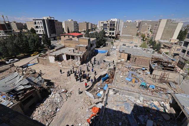 Media representatives gather around residential buildings that were damaged by recent strikes at Vahdat town in Karaj, southwest of Tehran on April 3, 2026. Iran and its allies traded fire with Israel and the United States, as Washington-linked assets across the Middle East were targeted alongside civilian infrastructure -- with the month-long war on April 3 showing little sign of easing. (Photo by ATTA KENARE / AFP) / 