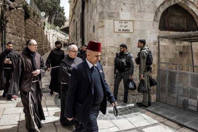 Israeli border guards stand by as a group of Franciscan friars marches past along the Via Dolorosa (Way of Suffering) during the Christian Good Friday procession in the old city of Jerusalem on April 3, 2026. (Photo by MARCO LONGARI / AFP)