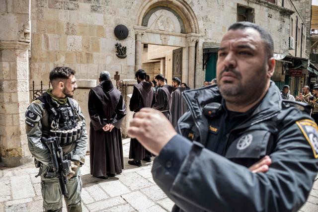 An Israeli policeman walks past a border guard as a group of Franciscan friars takes part in the Christian Good Friday procession along the Via Dolorosa (Way of Suffering) in the old city of Jerusalem on April 3, 2026. (Photo by MARCO LONGARI / AFP)