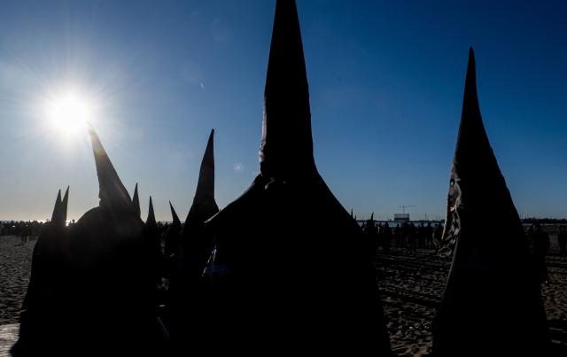 Hooded members of the "Cristo Salvador" (Christ the Savior) brotherhood take part in the Holy Week procession on the beach in Valencia on April 3, 2026. Christian believers around the world mark the holy week of easter in celebration of the crucifixion and resurrection of Jesus Christ. (Photo by Jose Jordan / AFP)