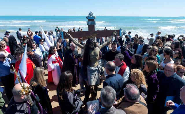 Penitents carry an effigy of the "Cristo Salvador y del Amparo" during Holy Week on the beach of Valencia on April 3, 2026. Christian believers around the world mark the holy week of easter in celebration of the crucifixion and resurrection of Jesus Christ. (Photo by Jose Jordan / AFP)