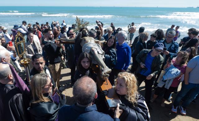 Penitents carry an effigy of the "Cristo Salvador y del Amparo" during Holy Week on the beach of Valencia on April 3, 2026. Christian believers around the world mark the holy week of easter in celebration of the crucifixion and resurrection of Jesus Christ. (Photo by Jose Jordan / AFP)