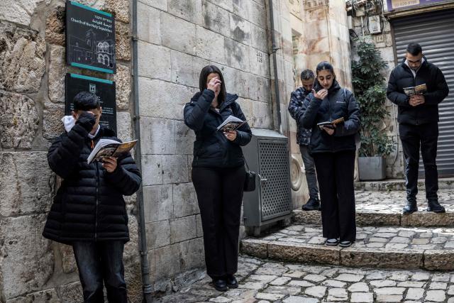 Catholic devotees cross themselves as they pray outside the closed gate accessing the the Church of the Holy Sepulchre in the old city of Jerusalem on April 3, 2026. (Photo by MARCO LONGARI / AFP)