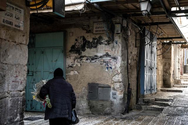 An Orthodox Christian nun walks with a bouquet of flowers through a deserted alley in the Christian Quarter in the old city of Jerusalem on April 3, 2026, during western observations of Holy Week and ahead of Orthodox Palm Sunday. (Photo by MARCO LONGARI / AFP)