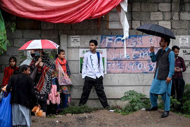 Passengers wait to board a government-run public bus at a stop during the rain in Islamabad on April 3, 2026. State-run public transport in Pakistan's capital and most populous province will be free for the coming month, officials said on April 3, after the government drastically raised fuel prices due to spiking global energy prices caused by the Iran war. (Photo by Farooq NAEEM / AFP)