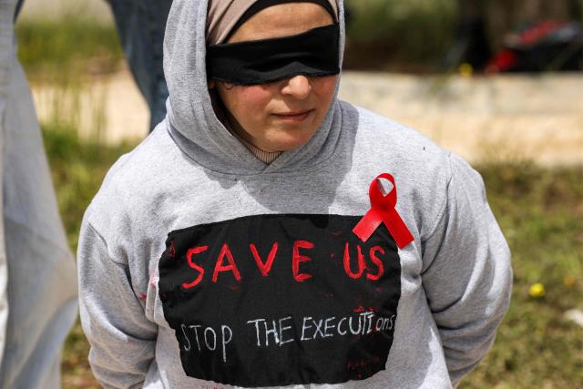 A protester wearing a blindfold with hands tied-up and a red ribbon on her chest attends a demonstration organised by the Israeli and Palestinian "Combatants for Peace" movement, against the recently-approved law allowing the execution of Palestinians convicted on terror charges for deadly attacks, at the Beit Jala North junction in the occupied West Bank on April 3, 2026. Under the new law, passed in parliament late on March 30, Palestinians in the West Bank convicted by military courts of carrying out deadly attacks classified as "terrorism" will face the death penalty as a default sentence. Because Palestinians in the territory are automatically tried in Israeli military courts, the measure effectively creates a separate and harsher legal track. (Photo by HAZEM BADER / AFP)