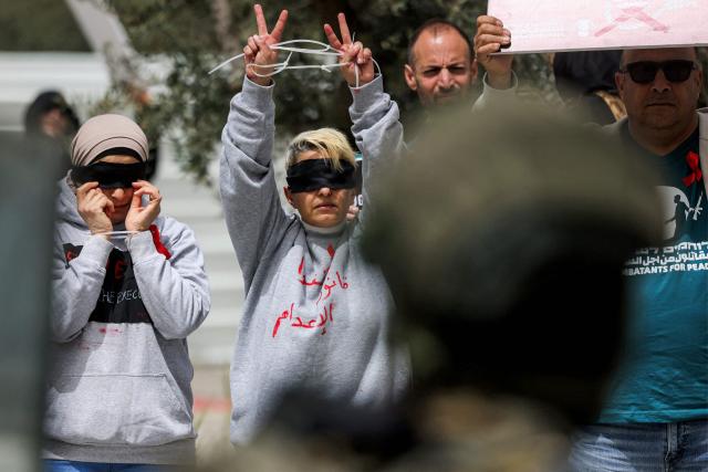 Israeli security forces stand before protesters gathering for a demonstration organised by the Israeli and Palestinian "Combatants for Peace" movement, against the recently-approved law allowing the execution of Palestinians convicted on terror charges for deadly attacks, at the Beit Jala North junction in the occupied West Bank on April 3, 2026. Under the new law, passed in parliament late on March 30, Palestinians in the West Bank convicted by military courts of carrying out deadly attacks classified as "terrorism" will face the death penalty as a default sentence. Because Palestinians in the territory are automatically tried in Israeli military courts, the measure effectively creates a separate and harsher legal track. (Photo by HAZEM BADER / AFP)