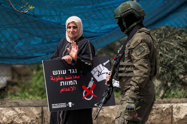 An Israeli security forces member stand before one of the protesters gathering for a demonstration organised by the Israeli and Palestinian "Combatants for Peace" movement, against the recently-approved law allowing the execution of Palestinians convicted on terror charges for deadly attacks, at the Beit Jala North junction in the occupied West Bank on April 3, 2026. Under the new law, passed in parliament late on March 30, Palestinians in the West Bank convicted by military courts of carrying out deadly attacks classified as "terrorism" will face the death penalty as a default sentence. Because Palestinians in the territory are automatically tried in Israeli military courts, the measure effectively creates a separate and harsher legal track. (Photo by HAZEM BADER / AFP)