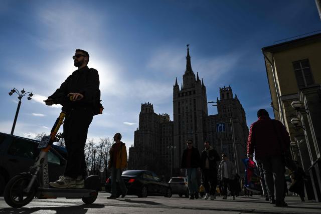 A person rides an electric scooter along Barrikadnaya street with one of the seven Stalinist skyscrapers known as the "Kudrinskaya Square Building" in the background in Moscow, on April 3, 2026 (Photo by Igor IVANKO / AFP)