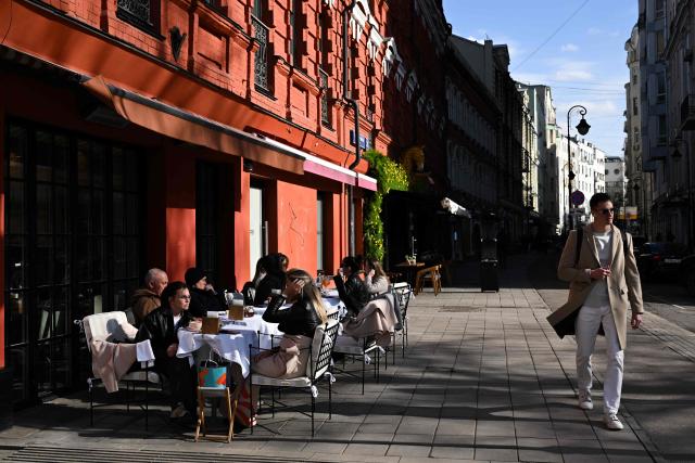 A pedestrian walks past a café's terrace where people are sitting on Malaya Bronnaya street in central Moscow, on April 3, 2026 (Photo by Igor IVANKO / AFP)