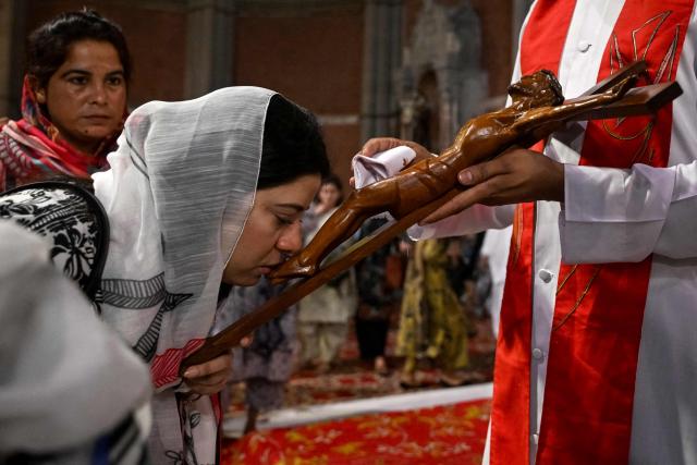 A Christian devotee kisses a depiction of the crucifixion of Jesus Christ during a Good Friday service at the Sacred Heart Cathedral Church in Lahore on April 3, 2026. (Photo by Arif ALI / AFP)