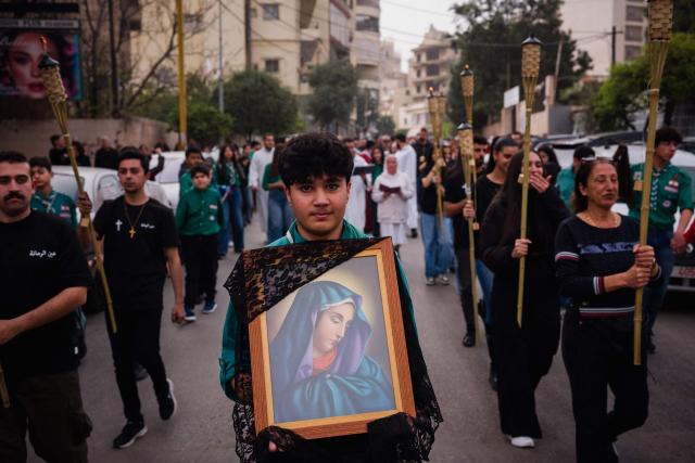 A scout carries the icon of the Virgin Mary during a Good Friday procession near the Saint Maroun Church in the Shiyah neighbourhood of Beirut's southeastern suburbs on April 3, 2026. Lebanon was drawn into the Middle East war on March 2 when Tehran-backed militant group Hezbollah launched attacks on Israel to avenge the killing of the Iranian leader. Israel has responded with broad strikes across Lebanon and a ground offensive. (Photo by Dimitar DILKOFF / AFP)