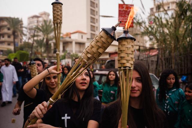 Lebanese Maronite Christian scouts hold torches during a Good Friday procession near the Saint Maroun Church in the Shiyah neighbourhood of Beirut's southeastern suburbs on April 3, 2026. Lebanon was drawn into the Middle East war on March 2 when Tehran-backed militant group Hezbollah launched attacks on Israel to avenge the killing of the Iranian leader. Israel has responded with broad strikes across Lebanon and a ground offensive. (Photo by Dimitar DILKOFF / AFP)