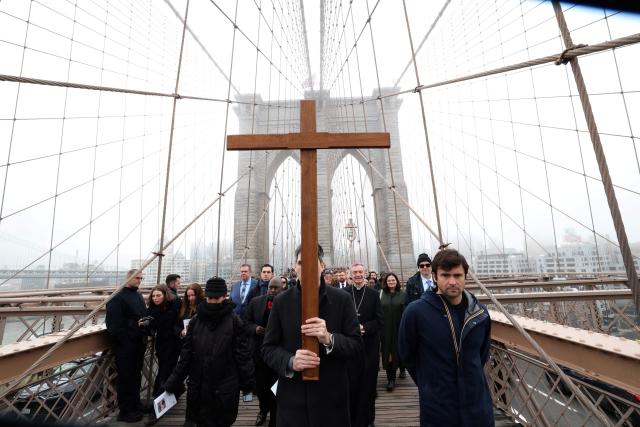 People participate in the “Way of the Cross” over the Brooklyn Bridge on Good Friday in New York on April 3, 2026. Christian believers around the world mark the Holy Week of Easter remembering the crucifixion and resurrection of Jesus Christ. (Photo by TIMOTHY A. CLARY / AFP)