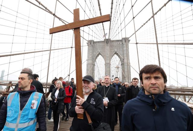 People participate in the “Way of the Cross” over the Brooklyn Bridge on Good Friday in New York on April 3, 2026. Christian believers around the world mark the Holy Week of Easter remembering the crucifixion and resurrection of Jesus Christ. (Photo by TIMOTHY A. CLARY / AFP)